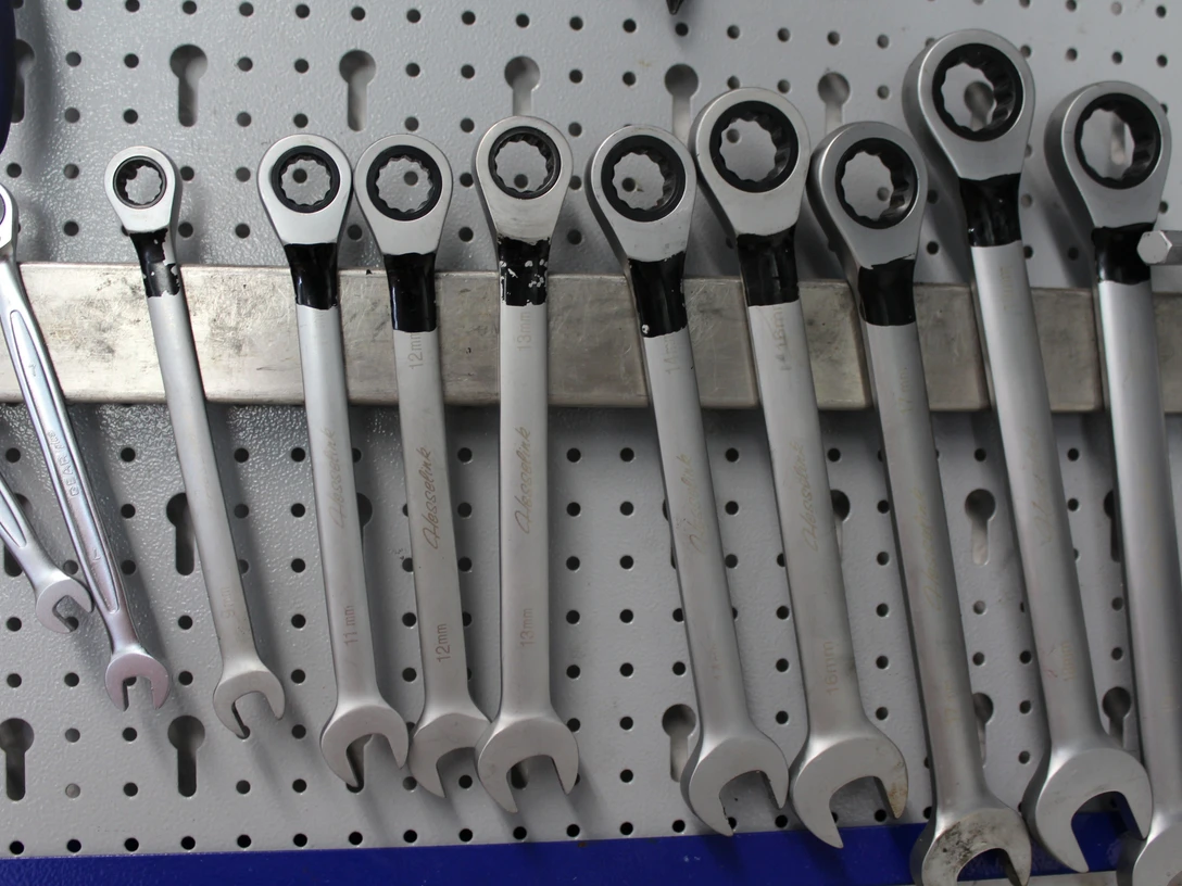 Fahrradservice Eine Reihe von silbernen Ratschen-Ringschlüsseln hängt ordentlich auf einer Lochwand.