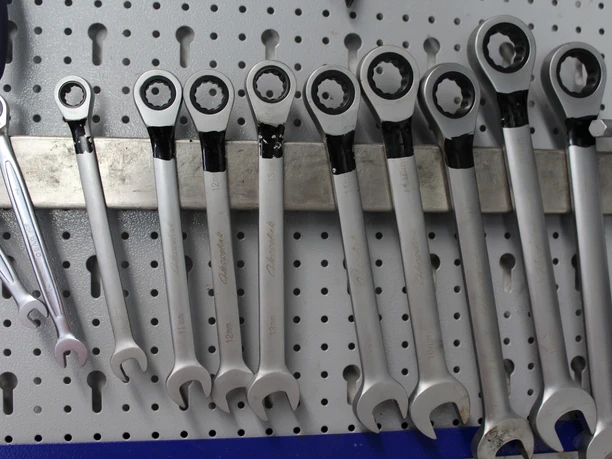 Fahrradservice Eine Reihe von silbernen Ratschen-Ringschlüsseln hängt ordentlich auf einer Lochwand.