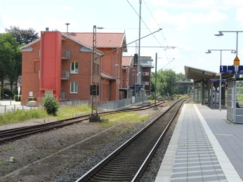 Kirchweyher Bahnhof Bahnhof Kirchweyhe mit roten Backsteingebäuden, Schienen und Bahnsteig bei sonnigem Wetter.
