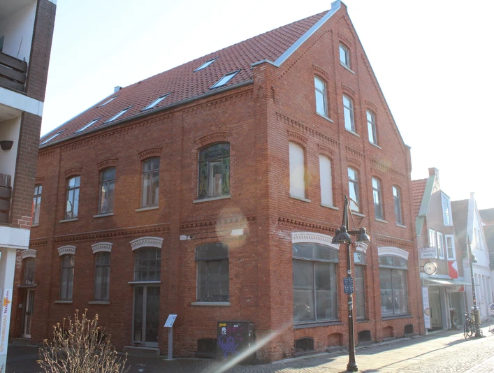 Biskuithaus Historisches rotes Backsteingebäude mit spitzem Giebel, großen Fenstern und Straßenlaterne davor.