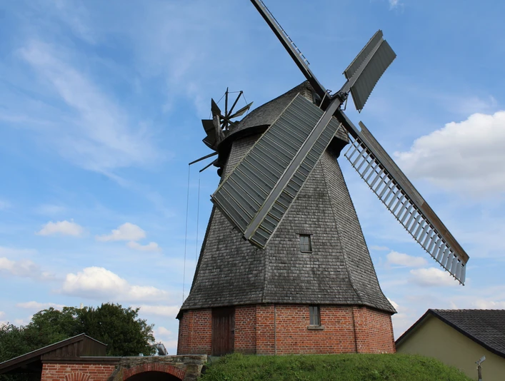 Büschings Mühle Petershagen Historische Windmühle mit Backsteinsockel und Holzverkleidung vor blauem Himmel in Petershagen.