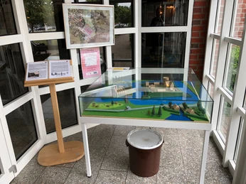 Ein detailliertes Modell zeigt die Burg Langwedel, umgeben von Bäumen, ausgestellt in einem Foyer.