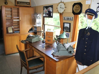 Ein historisches Lokomotivbüro mit antikem Mobiliar, Schreibmaschine und Uniform auf einem Kleiderständer.A historic locomotive office with antique furniture, typewriter and uniform on a clothes rack.Et historisk lokomotivkontor med antikke møbler, skrivemaskine og uniform på et tøjstativ.Een historisch locomotievenkantoor met antiek meubilair, typemachine en uniform op een kledingrek.