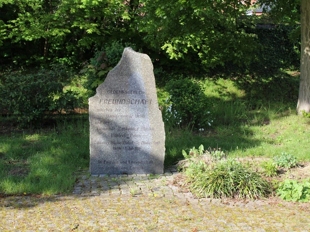 Gedenkstein im Grünen, umgeben von Bäumen und Büschen, mit der Aufschrift "Freundschaft", verbrieft und versiegelt im Jahr 1992.