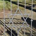 Jüdischer Friedhof Ein schmiedeeiserner Davidstern ziert das Tor eines Friedhofs, Schattenmuster auf dem Boden.