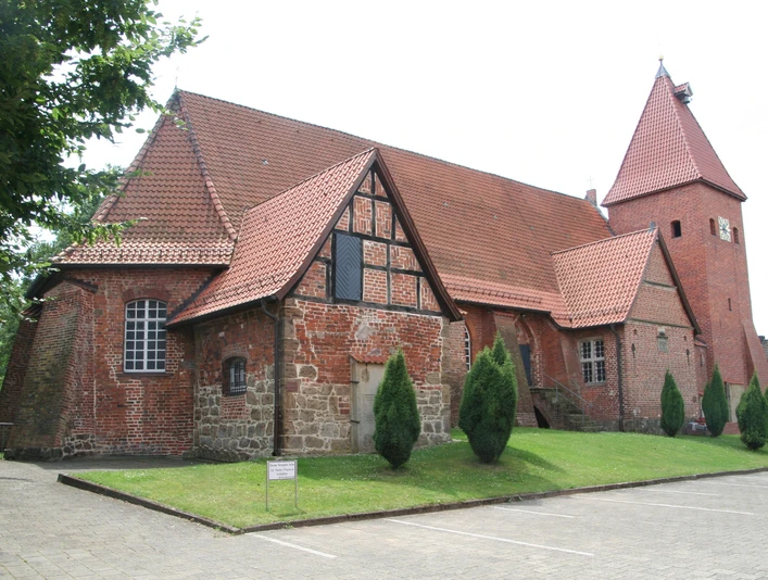 Backsteinkirche aus der Gotik in Drakenburg mit markantem Schnittgiebel und vereinzelt stehenden Bäumen.