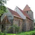 Kirche Buchholz Eine historische Steinkirche mit roten Ziegeldächern, umgeben von Bäumen und grünem Rasen.