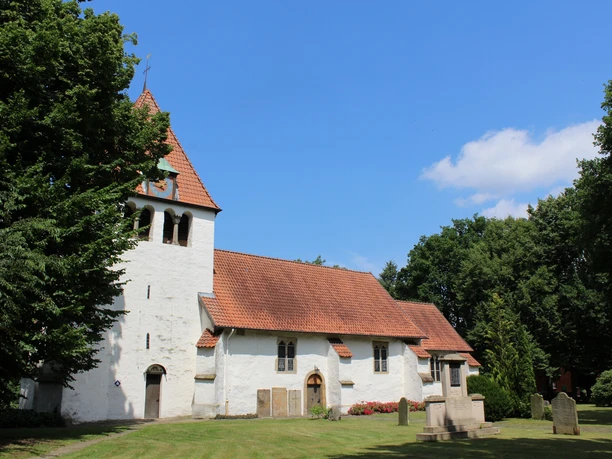 Kirche Heimsen Eine weiße Kirche mit rotem Ziegeldach, umgeben von grünen Bäumen und einem gepflegten Rasen.