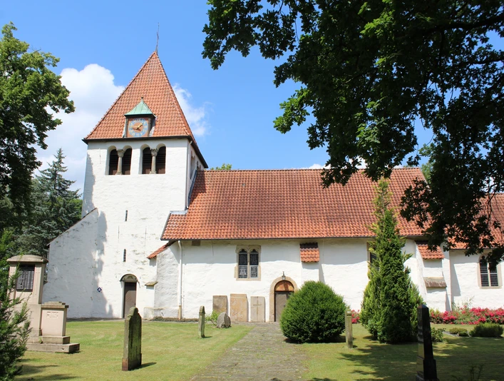 Kirche Heimsen Eine weiße Kirche mit rotem Ziegeldach, umgeben von Rasen und Bäumen, im historischen Stil.