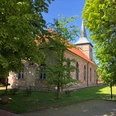 Die Kirche Landesbergen steht malerisch umgeben von grünen Bäumen und gepflegtem Rasen.