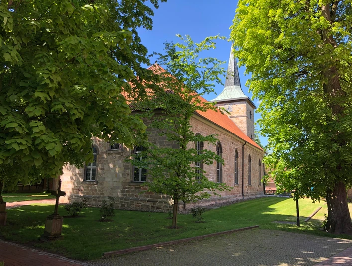 Die Kirche Landesbergen steht malerisch umgeben von grünen Bäumen und gepflegtem Rasen.