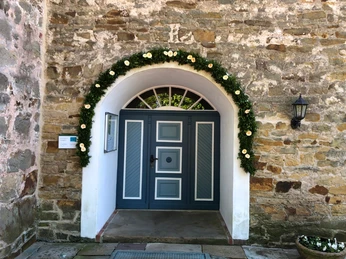 Kirche Landesbergen Eingangsportal aus Holz mit Blumengirlande an einem historischen Sandsteingebäude in Landesbergen.