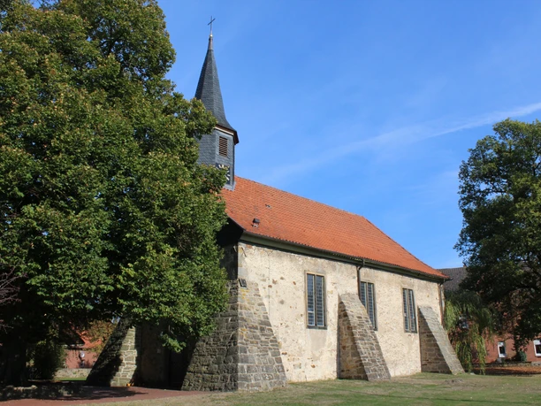 Kirche Münchehagen Eine historische Dorfkirche in Münchehagen, umgeben von Bäumen, mit einem markanten Kirchturm.