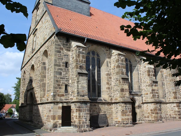 Petrikirche Eine Kirche mit roten Ziegeln und gotischen Fenstern; eingefasst von Bäumen und umgeben von Straßen.