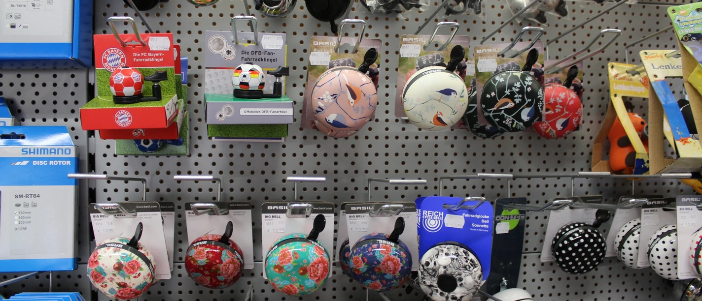 Fahrradklingel Verschiedene farbenfrohe Fahrradklingeln hängen an einer perforierten Verkaufswand in einem Geschäft.