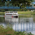Das Fahrgastschiff Bremen passiert die Weserbrücke bei Nienburg auf einem grünen, ruhigen Fluss.