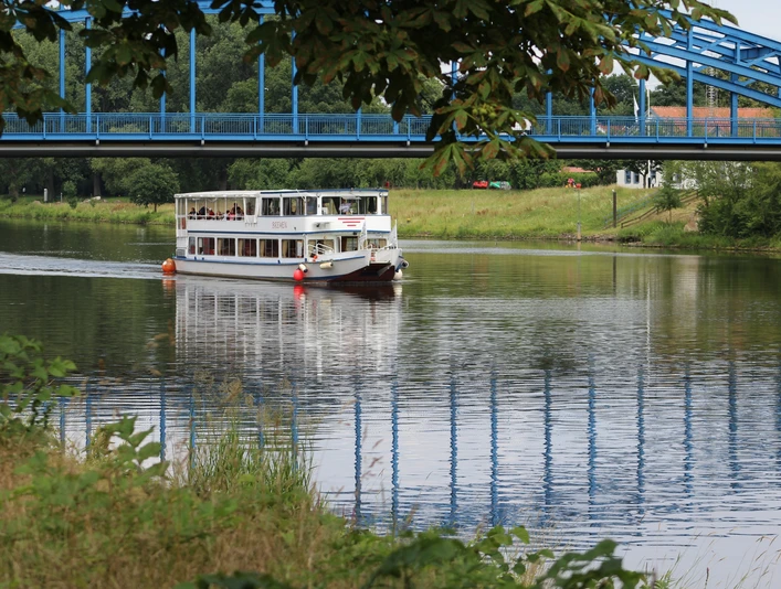 Das Fahrgastschiff Bremen passiert die Weserbrücke bei Nienburg auf einem grünen, ruhigen Fluss.