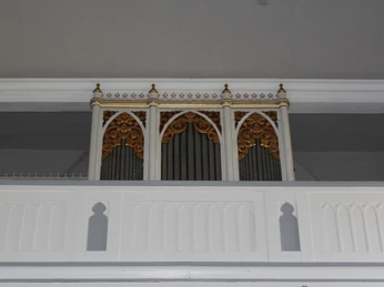 Friederikenkapelle Orgel Eine kunstvoll verzierte Orgel in weißem Gehäuse mit goldenen Details, eingebaut in eine Kapelle.