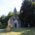 Friederikenkapelle Eine historische Kapelle mit gotischen Elementen, umgeben von üppigem Grün und einem Gedenkstein.