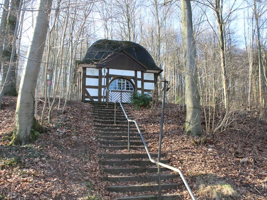 Friedrichspavillon mit Fachwerkstruktur, von Laubbäumen umgeben, auf einer Anhöhe erreichbar.