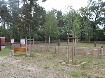 Gedenkstätte Heemsen mit Informationstafeln, Gedenksteinen, jungen Bäumen und einem Holzzaun.