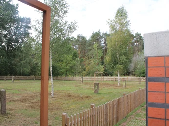 Gedenkstätte Heemsen Denkmalstätte mit Gedenksteinen und Zaun, umgeben von Bäumen und einem bewölkten Himmel.