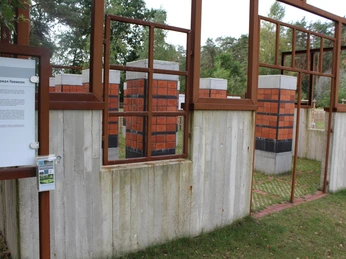 Gedenkstätte Heemsen Gedenkstätte aus rostigem Stahl und Beton mit Info-Tafel, umgeben von Bäumen und grüner Wiese.