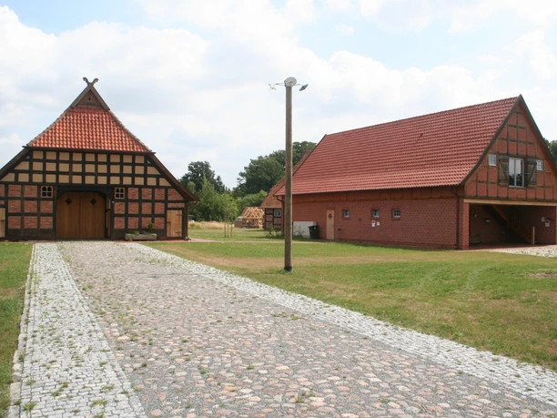 Two traditional half-timbered buildings with red-tiled roofs stand along a cobblestone path.