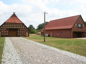 Ehmken Hoff Zwei traditionelle Fachwerkgebäude mit roten Ziegeldächern stehen an einem gepflasterten Weg.