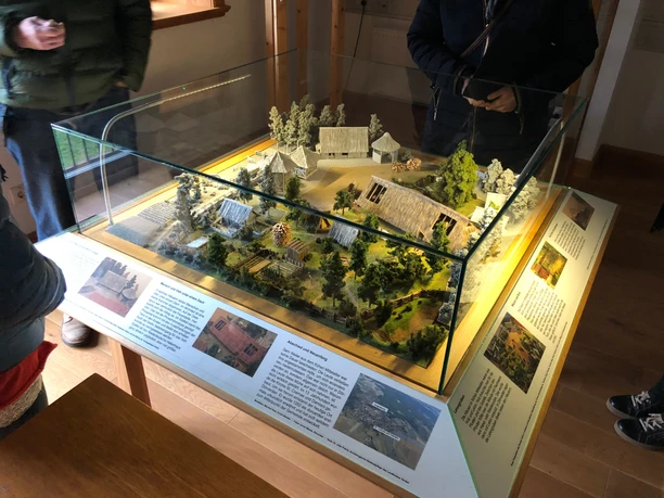 Ein detailliertes Modell des Ehmken Hoff, umgeben von Miniaturbäumen, präsentiert in einer Glasvitrine.