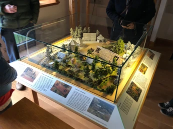 Ehmken Hoff Modell Ein detailliertes Modell des Ehmken Hoff, umgeben von Miniaturbäumen, präsentiert in einer Glasvitrine.