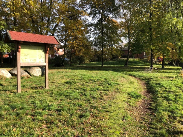 Grabhügelfeld in Nienburg Wegweiser führt zu einem Grabhügelfeld in Nienburg, umgeben von herbstlich gefärbten Bäumen.