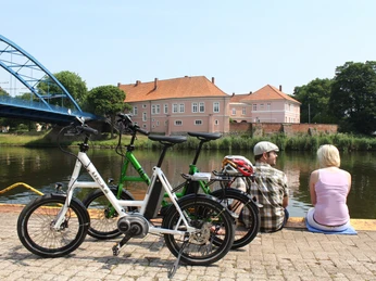 Grafenschloss zu Hoya Das Grafenschloss Hoya spiegelt sich im Fluss wider, während Radfahrer eine Pause am Ufer einlegen.Hoya Castle is reflected in the river as cyclists take a break on the banks.Hoya Slot spejler sig i floden, mens cyklisterne tager en pause på bredden.Hoya Castle wordt weerspiegeld in de rivier terwijl fietsers een pauze nemen aan de oever.