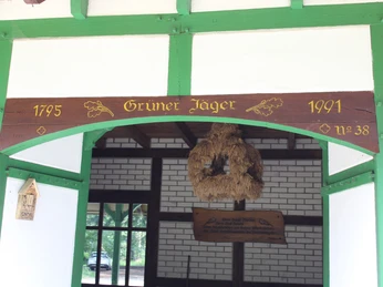 Grüner Jäger Darlaten Holzverzierte Eingangsfront des Gasthofs Grüner Jäger Darlaten mit Eichendekor und Jahreszahlen.