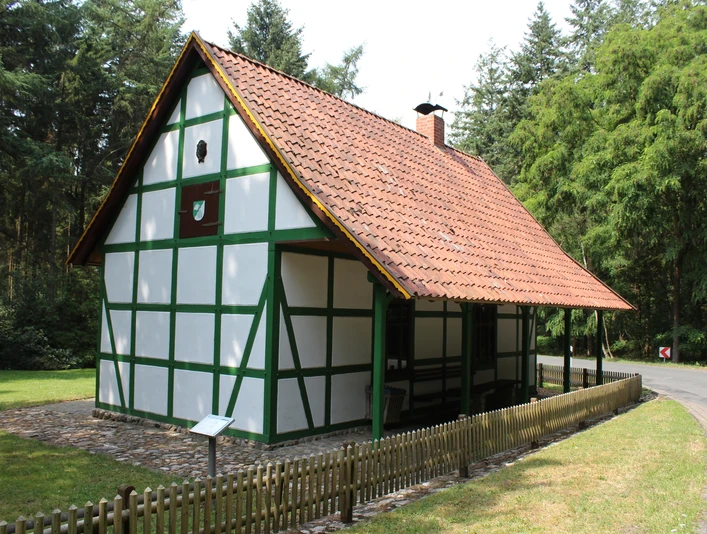 Grüner Jäger Darlaten Ein historisches, mit Fachwerk gestaltetes Haus im Grünen, umgeben von dichten Bäumen und Wiese.