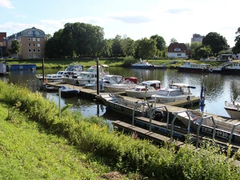 Nienburger Hafen Boote liegen am Steg im Nienburger Hafen vor Anker, umgeben von grüner Vegetation und Gebäuden.Boats are moored at the jetty in Nienburg harbor, surrounded by green vegetation and buildings.Bådene ligger fortøjet ved anløbsbroen i Nienburg havn, omgivet af grøn vegetation og bygninger.Boten liggen aan de steiger in de haven van Nienburg, omringd door groene vegetatie en gebouwen.