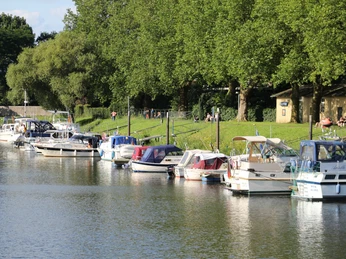 Boote im Wasser, vertäut an einem ruhigen Kai mit üppig grünem Ufer und Bäumen im Hintergrund.Boats in the water, moored on a quiet quay with a lush green shore and trees in the background.Både i vandet, fortøjet på en stille kaj med en frodig grøn bred og træer i baggrunden.Boten in het water, aangemeerd aan een rustige kade met een weelderig groene oever en bomen op de achtergrond.