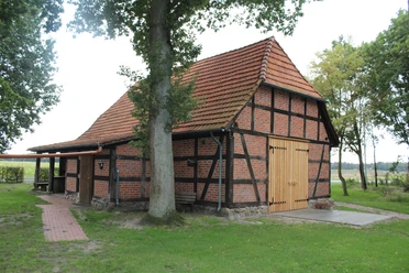 Heimathaus Voigtei Ein historisches Fachwerkhaus mit roten Backsteinen und einem Ziegeldach auf einer grünen Wiese.