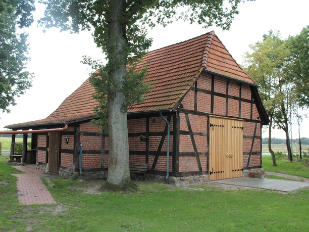 Heimathaus Voigtei Ein historisches Fachwerkhaus mit roten Backsteinen und einem Ziegeldach auf einer grünen Wiese.