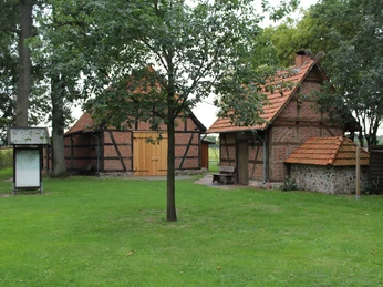 Heimathaus Voigtei Zwei historische Fachwerkgebäude mit roten Ziegeldächern in einer grünen Umgebung mit Bäumen.