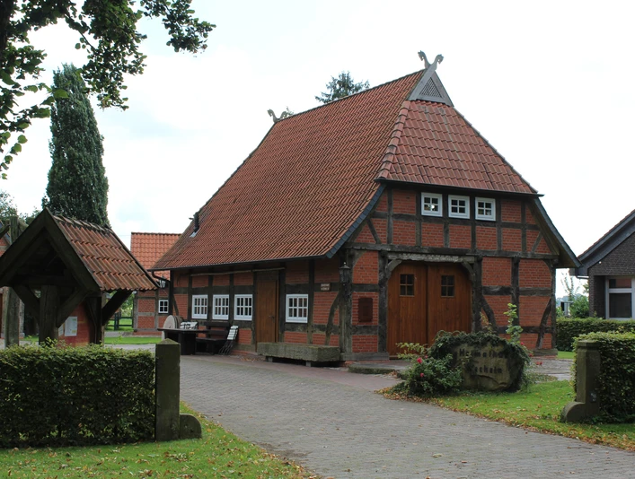 Heimathaus Wechold Historisches Fachwerkhaus mit Ziegeldach und Brunnendekor, umgeben von Bäumen in ruhiger Lage.
