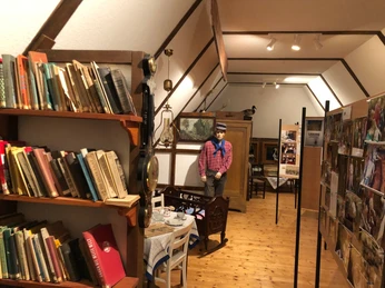 Bibliothek und Ausstellungsraum mit Holzboden, gefüllt mit Büchern und Heimat-Dekor, ein Skulpturen-Pfad.