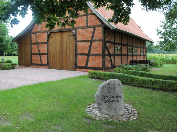Heimathaus Deblinghausen Ein traditionelles Fachwerkgebäude mit rotem Ziegeldach und Holztoren, umgeben von grünem Rasen.