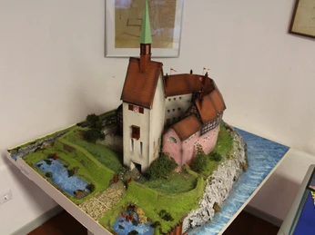 Heimatmuseum Grafschaft Hoya Miniaturmodell eines historischen Gebäudes mit Fachwerk und Turm, umgeben von Flusslandschaft.