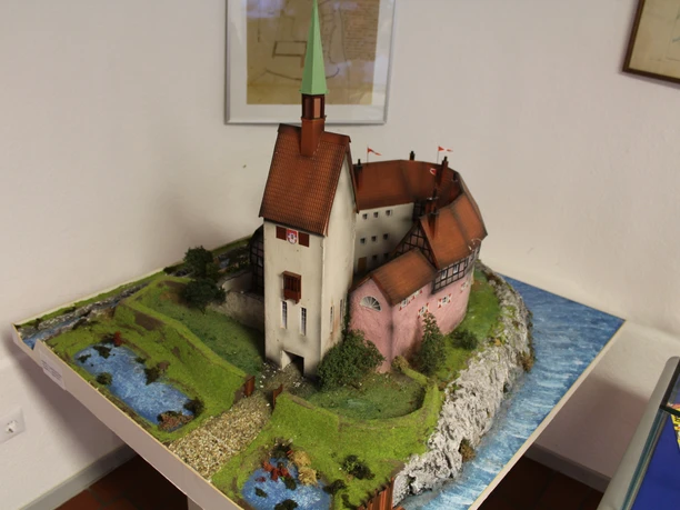 Heimatmuseum Grafschaft Hoya Miniaturmodell eines historischen Gebäudes mit Fachwerk und Turm, umgeben von Flusslandschaft.