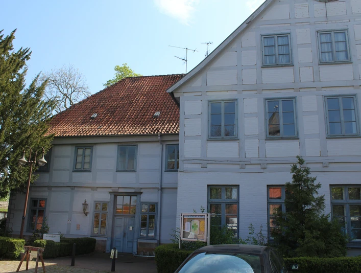 Ein historisches Fachwerkgebäude mit rotem Ziegeldach und weißen Fassaden dominieren das Bild.