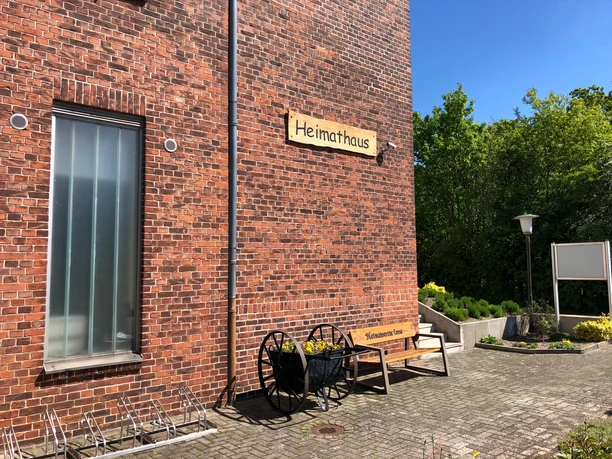 Heimatmuseum Leese Heimatmuseum Leese: Roter Ziegelbau mit Bank und Rad, umgeben von grünen Bäumen bei blauem Himmel.