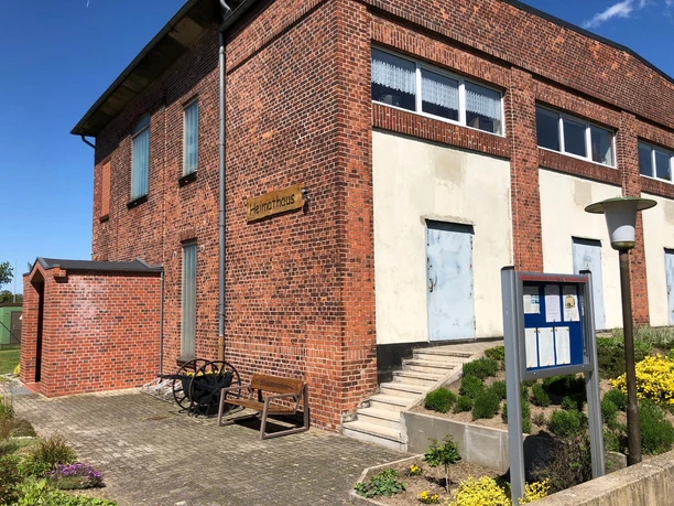 Heimatmuseum Leese Backsteingebäude mit Heimatmuseumschild, historischer Wagenrad-Dekoration und Blumenrabatten.
