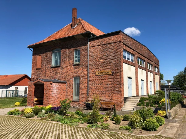 Heimatmuseum Leese, historisches Backsteingebäude mit gepflegtem Garten und blühenden Pflanzen.