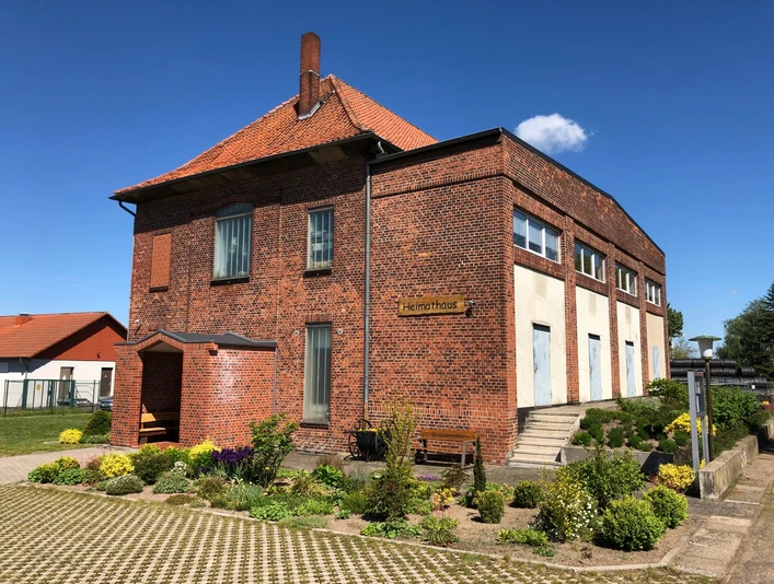 Heimatmuseum Leese, historisches Backsteingebäude mit gepflegtem Garten und blühenden Pflanzen.